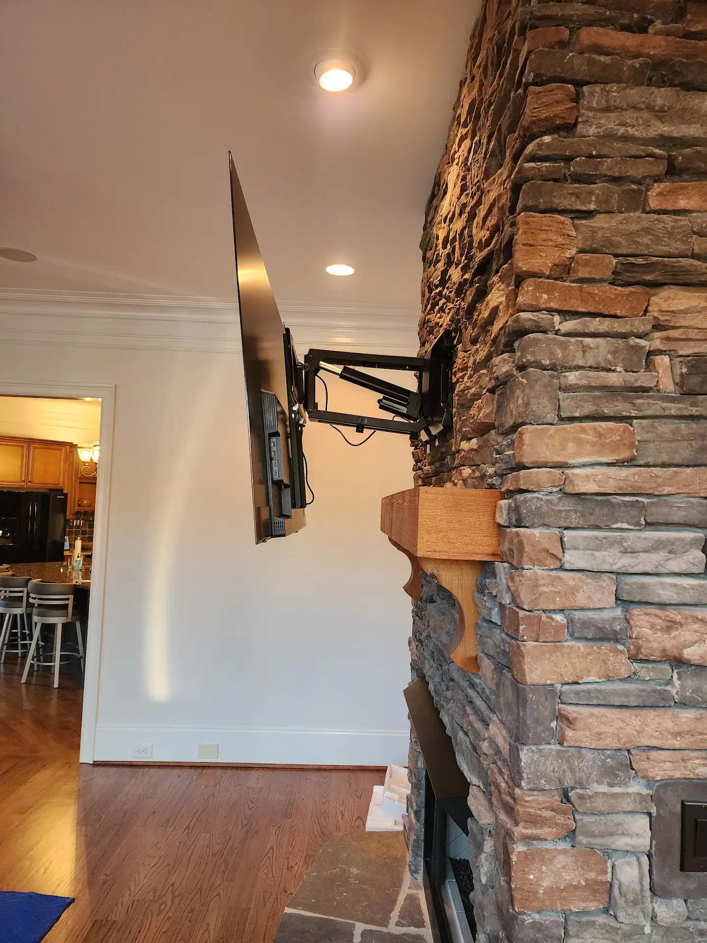 Tv mounted above a stone fireplace in charlotte nc with builder-grade masonry anchors by south charlotte services